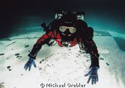 Technical diver on ice. Posed upside-down under the ice i... by Michael Grebler 